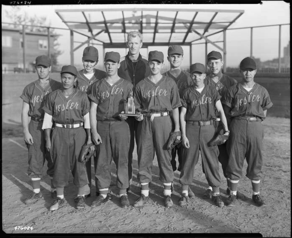 In 1946, Seattle's Parks Department began recreational programs at the Yesler Terrace Community Center in Seattle, WA and its playfield. This 1947 photo shows the members of the Yesler boys' baseball team at Yesler Playground with their coach and their trophy. Museum of History & Industry Collection.