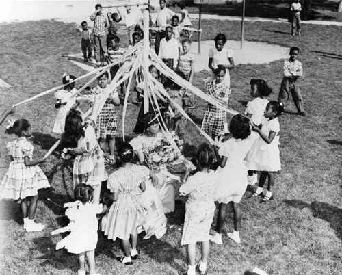 Children dance around the maypole on May 1, 1952, at the Jordan Downs Housing Project, located in the Watts section of Los Angeles, CA. Los Angeles Public Library Photo Collection.