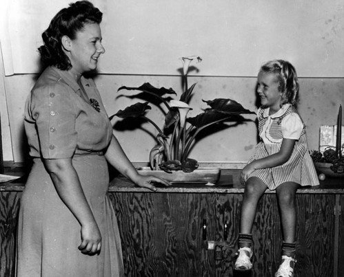 Residents of the Channel Heights Housing Project in San Pedro, CA pose with flower arrangements at a flower show held at the housing projects. Los Angeles Public Library Photo Collection.