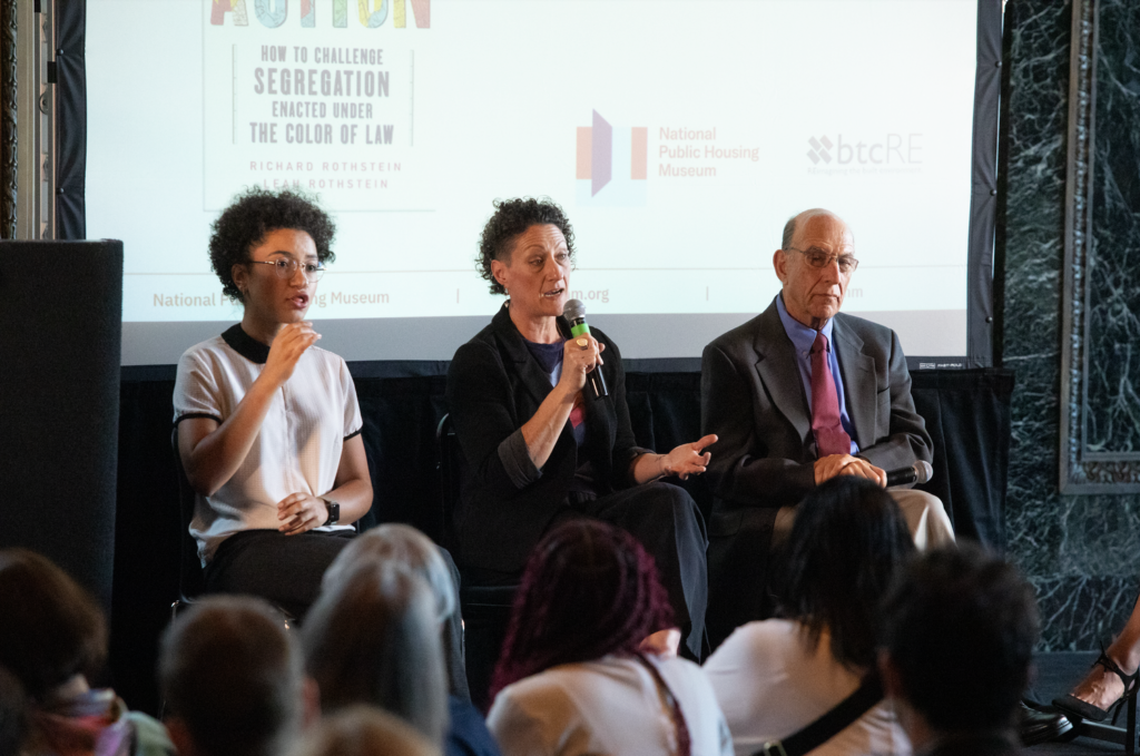 ASL interpreter Makeda Duncan, Leah Rothstein, and Richard Rothstein sit in a row in front of a screen at the Chicago Cultural Center.