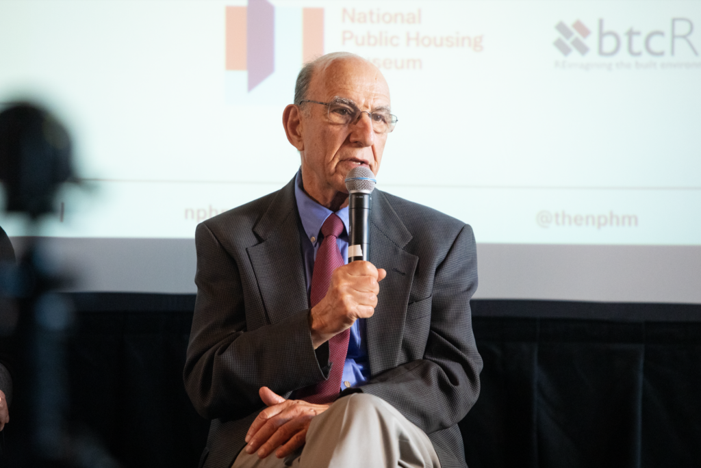 Richard Rothstein speaks into a microphone while seated.