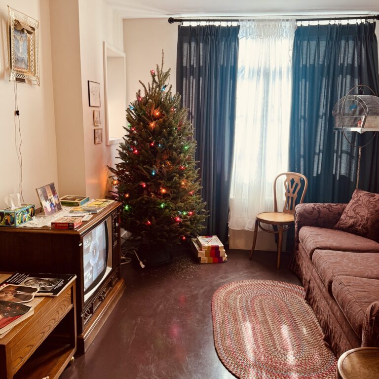 A Christmas tree strung with holiday lights in a vintage apartment