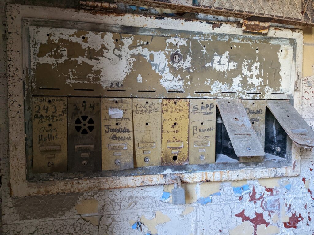 Rusted metal mailboxes with several names written and crossed out.