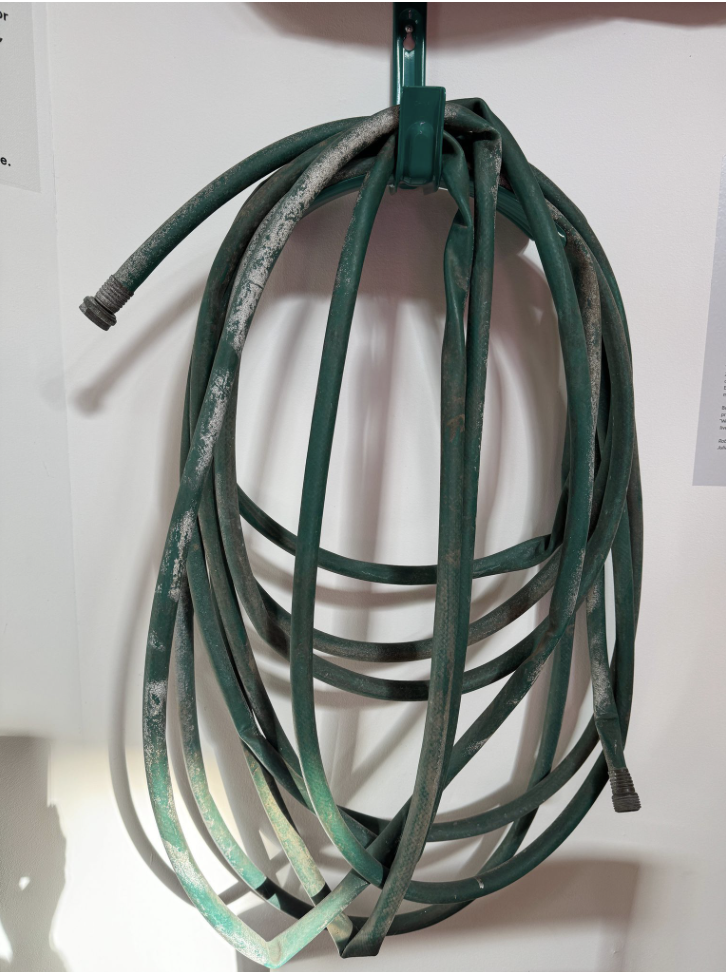 Green water hose hanged on the wall