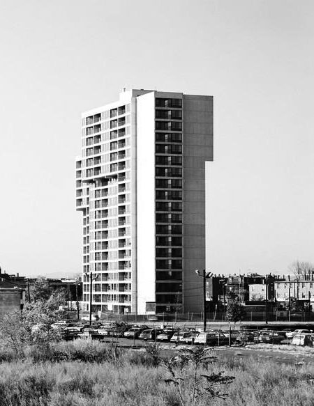 An apartment tower rises above a field