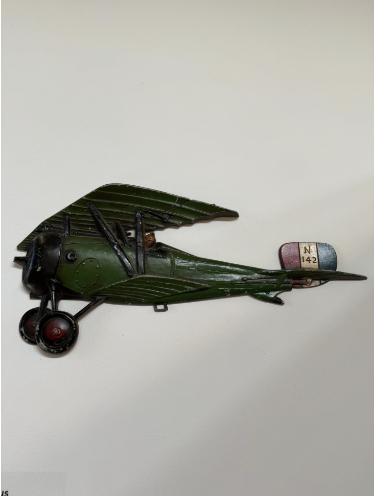 Classic light aircraft artifact made of metal. The airplane is primarily green with red, white, and blue on the tailpiece.