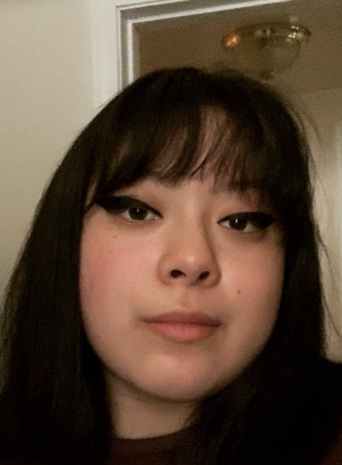 A photo of Juanairis Castaneda. The photo is a close up of Juanairis, a Latinx nonbinary person. She has long black hair and bangs and is wearing dark cat-eye eyeliner.