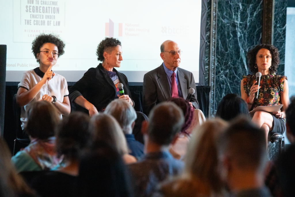 ASL interpreter Makeda Duncan, Leah Rothstein, and Richard Rothstein sit in a row in front of a screen at the Chicago Cultural Center.