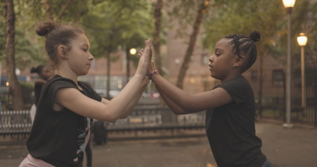 Two girls playing a hand clapping game outside