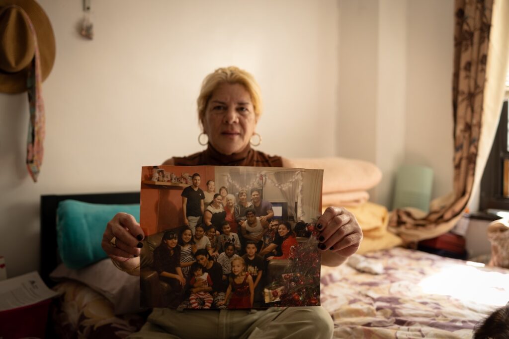 A woman holds a photo of a large family gathering up to the camera