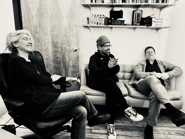 Silvertone image of three people sitting in an office laughing