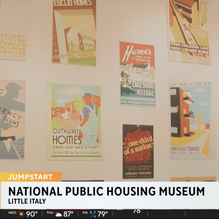 Still of news broadcast showing an installation of housing posters