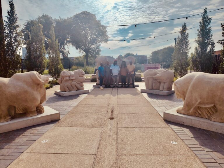 Five people pose in front of an animal sculpture at the National Public Housing Museum
