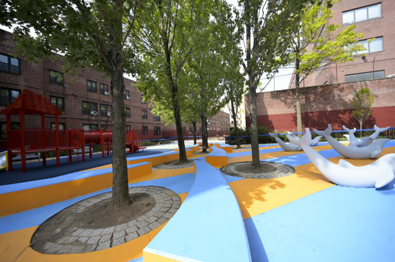 A brightly colored play surface in between residential building, with dolphin sculptures.