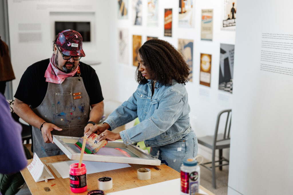 Two people making a screenprint poster