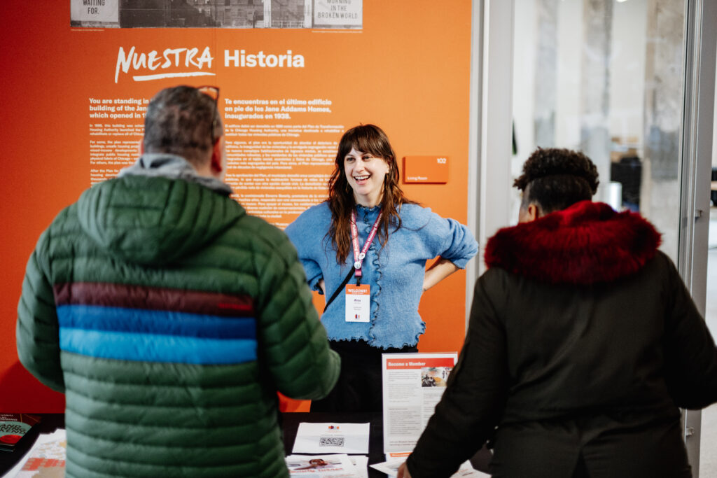 A person wearing a staff badge talking with museum guests