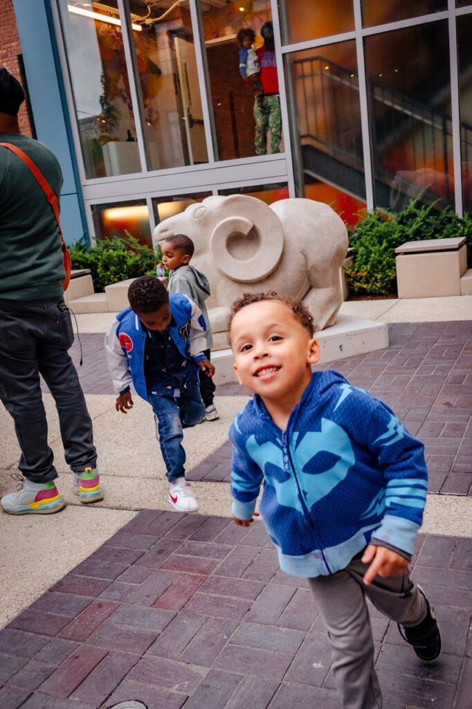 Kids playing in a courtyard with an animal sculpture in the background