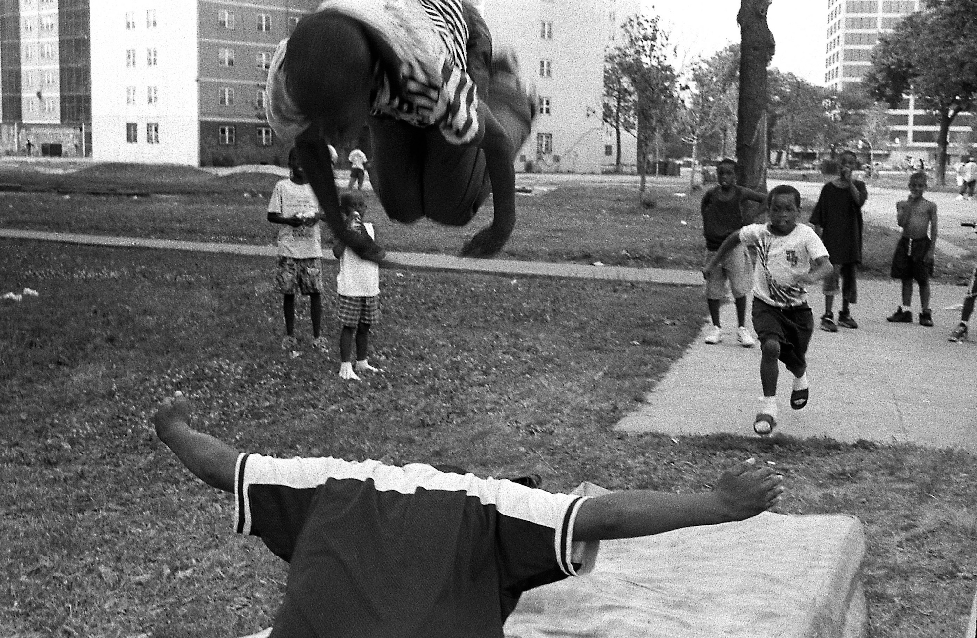 Kids tumbling on mattresses outside of a high-rise apartment