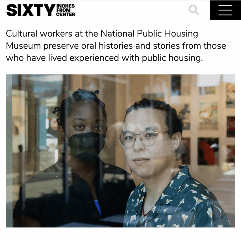 Screenshot of an article includes a photo of two people stand perpendicular to each other closely behind a window in an exhibition space.