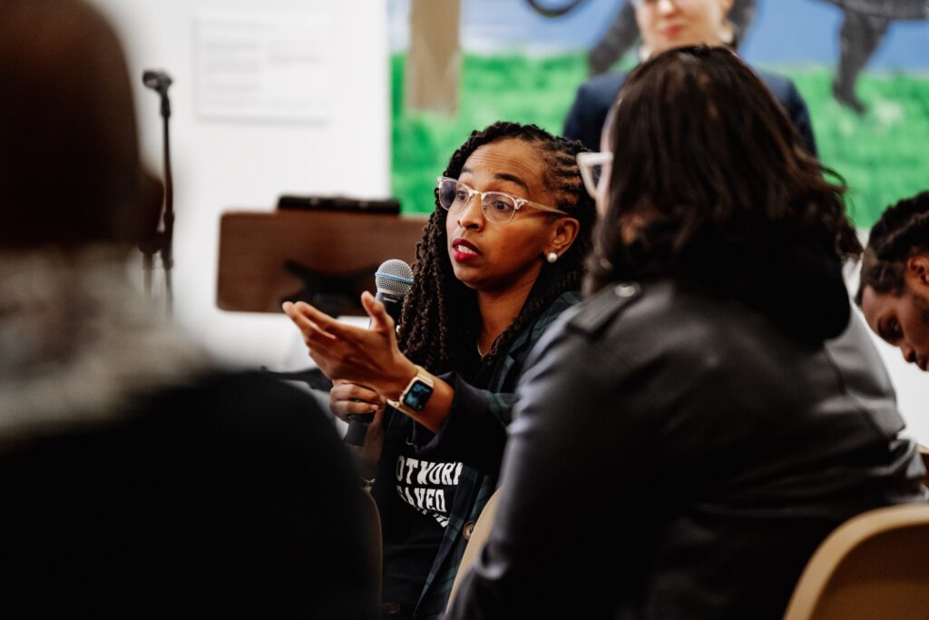 A person seated with a microphone talking at an event