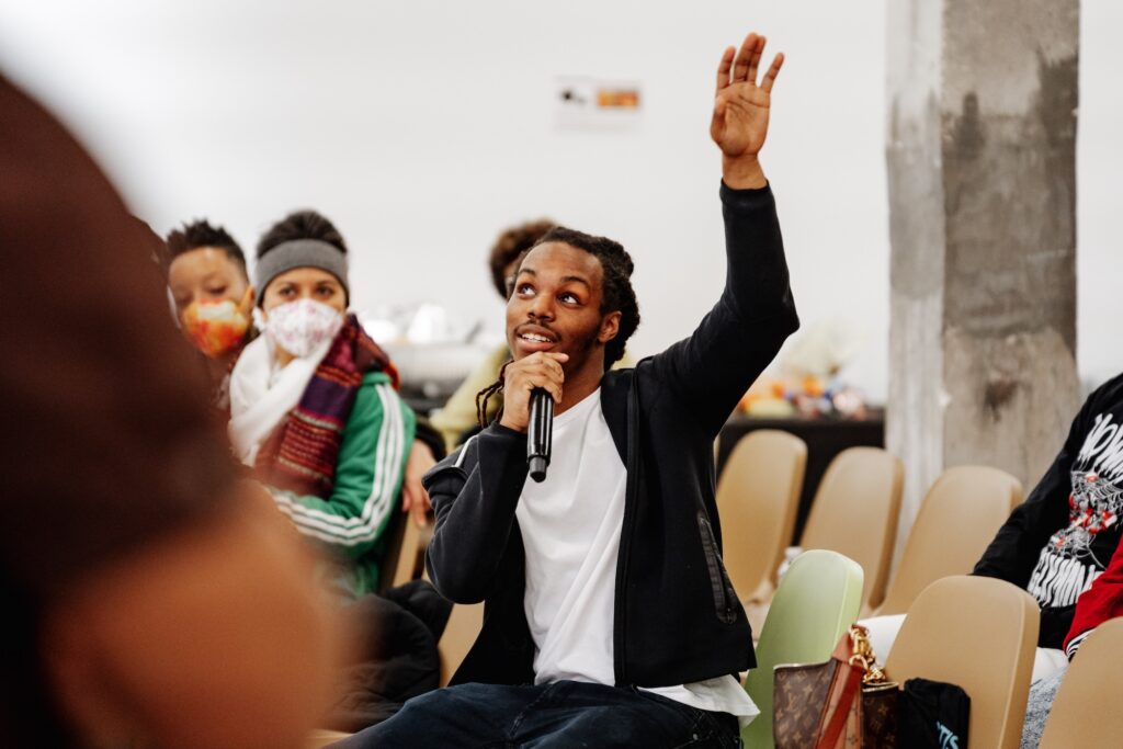 A person with a microphone raises their hand