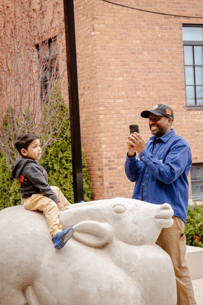 A kid poses for a photo on top of a animal sculpture