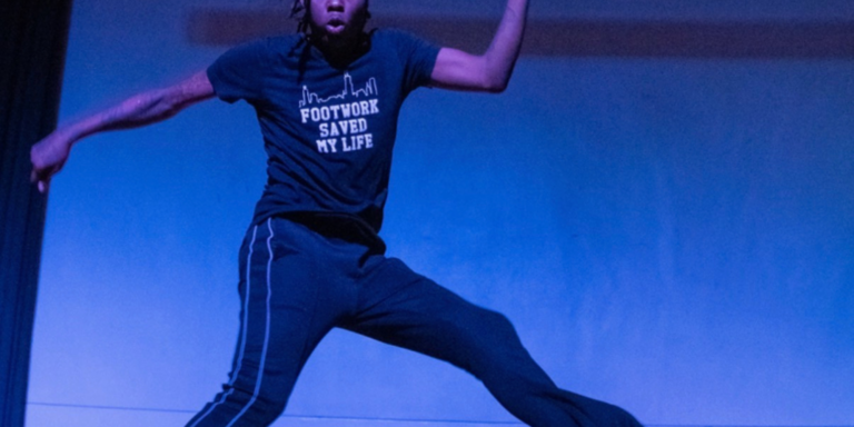 Dancing on stage wearing a t-shirt that reads Footwork Saved My Life