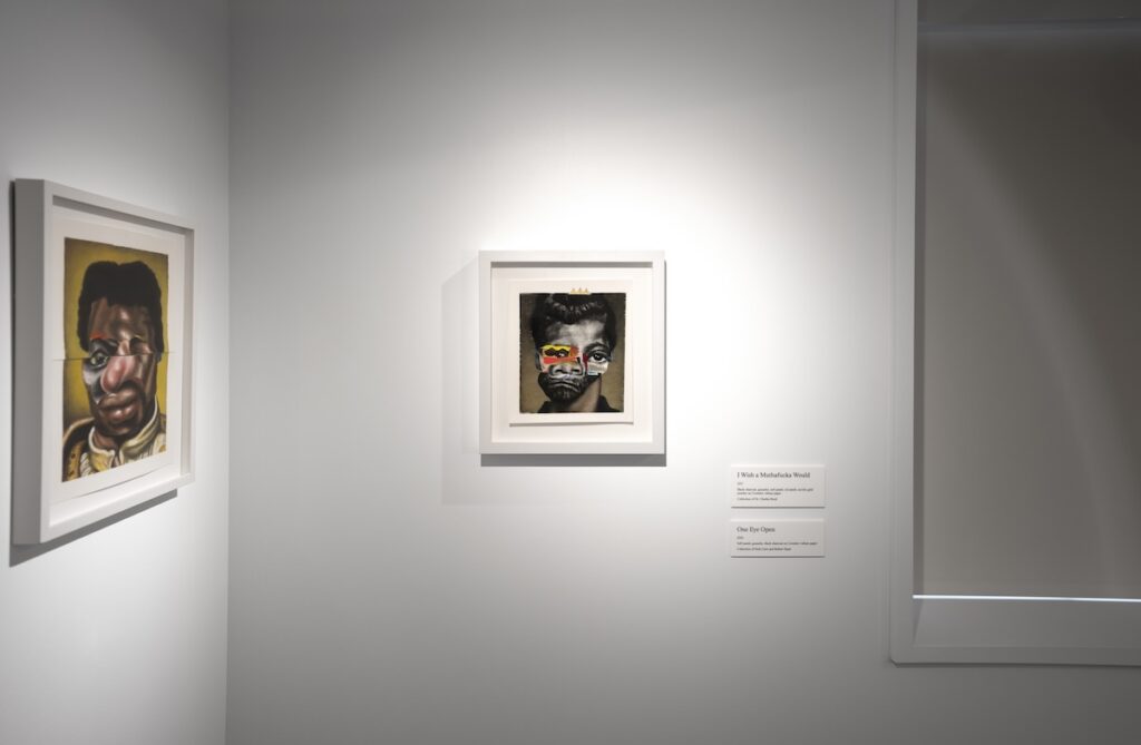 Two small portraits displayed in the corner of a gallery, nearby placards give them the titles I Wish a Muthafucka Would, and One Eye Open