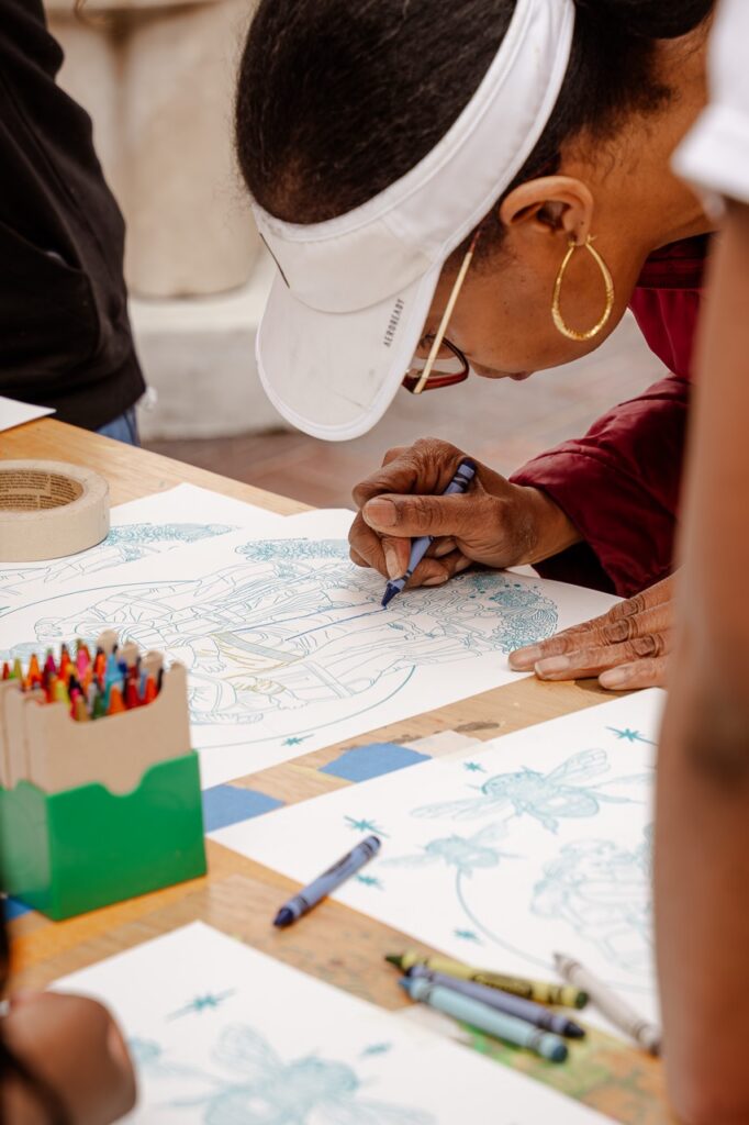 Close-up of a person using crayons to color in a screen printed sheet