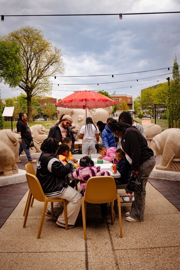 People gather around a table to make art in sculpture garden at the National Public Housing Museum