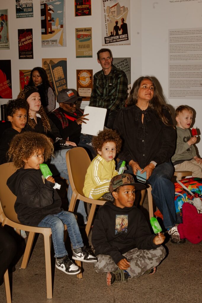 All-ages crowd enjoying ice pops and waiting for a performance at the National Public Housing Museum