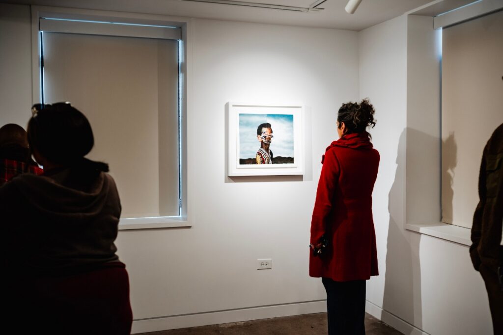 A person in a red coat looking at a framed artwork in a gallery