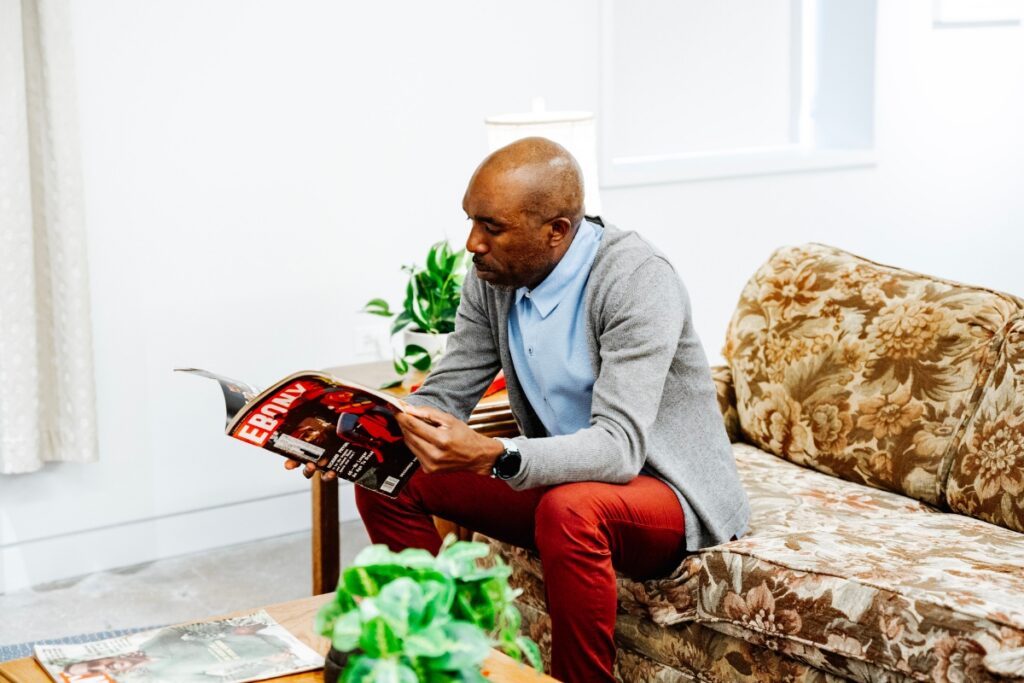 A person flips through a vintage Ebony magazine while sitting on a couch