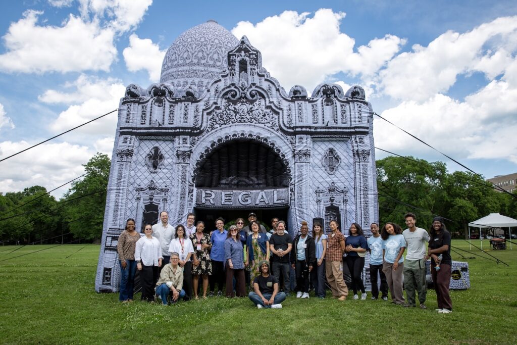 A diverse group of people pose in front of an inflatable artwork