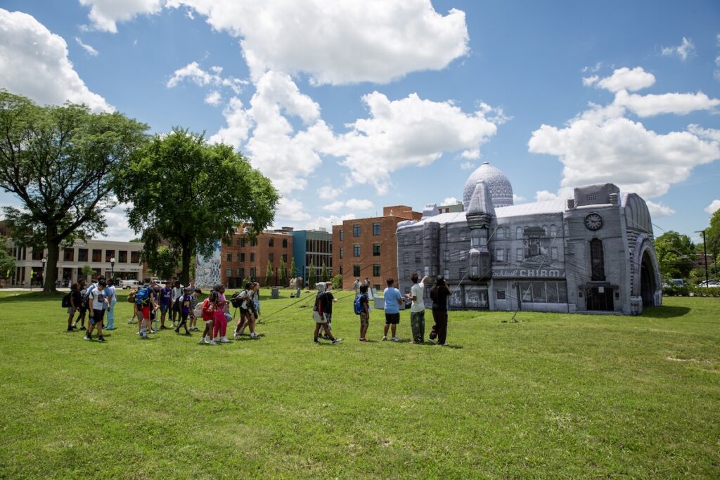 People gather in a field around a white inflatable building