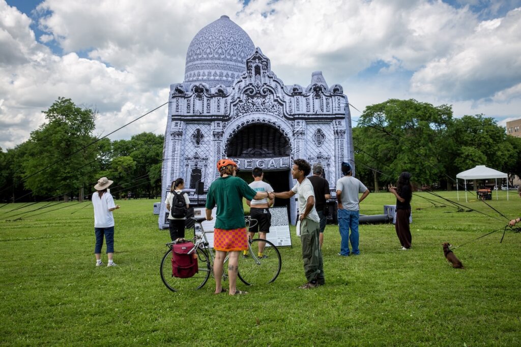 A bicyclist and others gather around a white inflatable structure