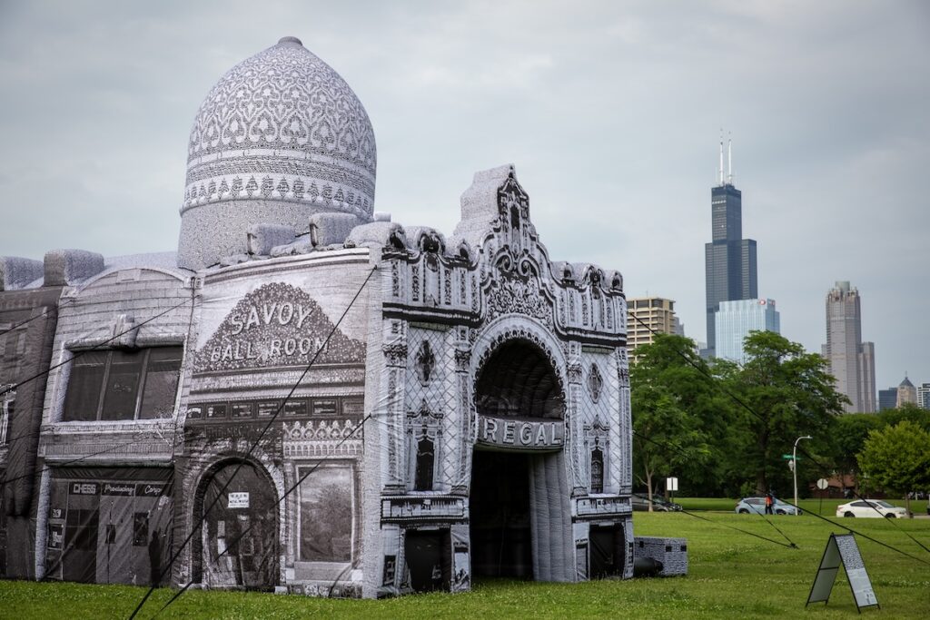 A white inflatable building evoking the Savoy Ballroom and Regal Theater, with the Chicago skyline in the distance