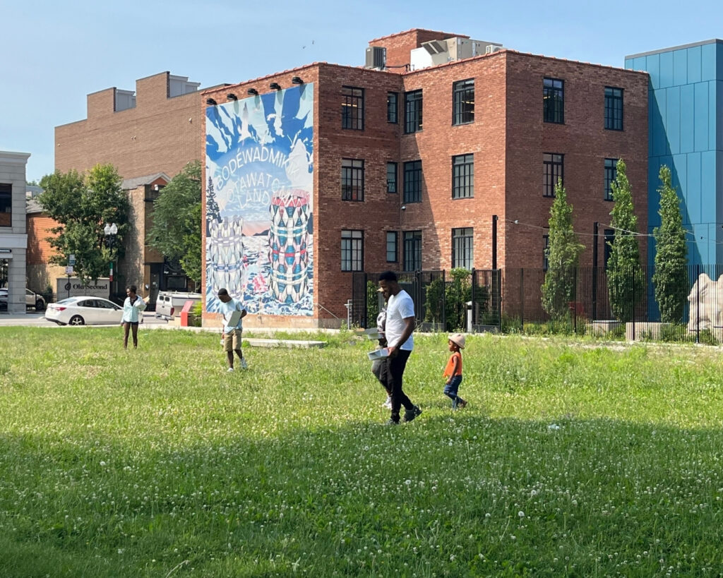 People walking through a field, with the museum in the background